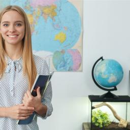 Junge Frau, lächelnd, steht vor einer Weltkarte