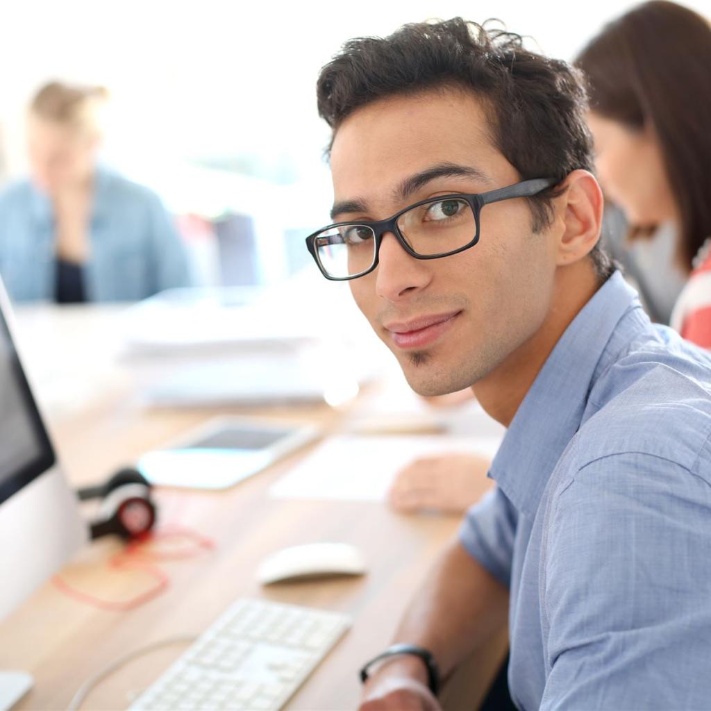 Ein junger Fachangestellter sitzt vor seinem Bildschirm