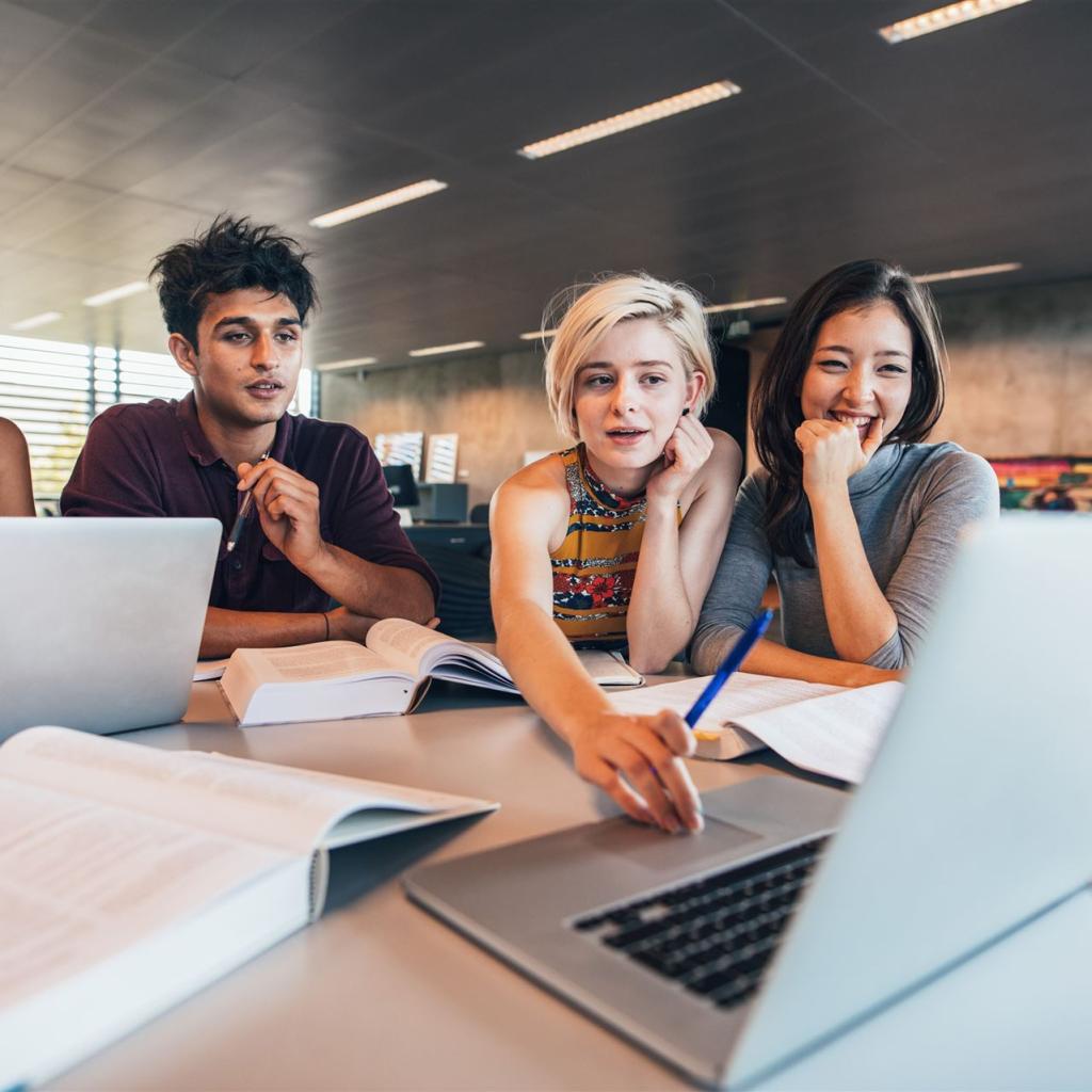 Eine Gruppe junger E-Commerce Kaufleute sitzen vor dem Laptop und diskutieren über ein Konzept