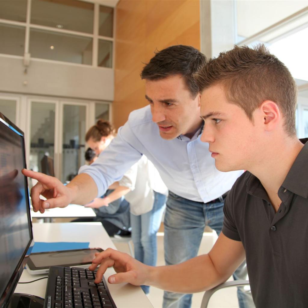 Ein Student und sein Mentor vor einem großen Computerbildschirm